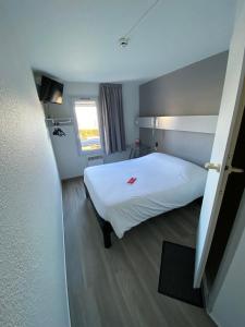 1 dormitorio con cama blanca y ventana en Fasthotel, en Jaux