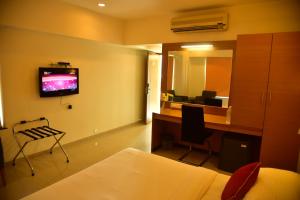 a hotel room with a desk and a television on the wall at Hi 5 Hotel & Experience in Nashik