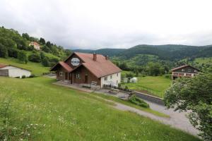 uma casa numa colina com um campo verde em Les Chantenées em La Bresse