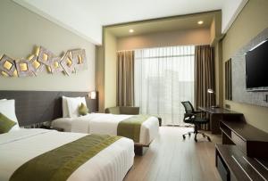 um quarto de hotel com duas camas e uma secretária em Holiday Inn Cikarang Jababeka, an IHG Hotel em Cikarang