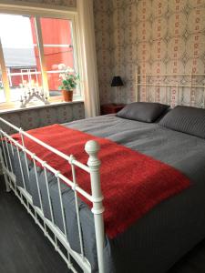 a bedroom with a bed with a red blanket on it at Ollestad gård in Ljung