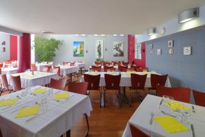 un comedor con mesas blancas y sillas rojas en Hotel CIS Paris Kellermann en París