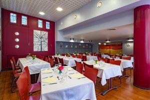 une salle à manger avec des tables blanches et des murs rouges dans l'établissement Hotel CIS Paris Kellermann, à Paris