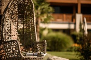 une chaise en osier avec un livre assis sur elle dans l'établissement Sonnen Resort, à Naturno