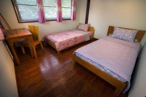 a bedroom with two beds and a table and a window at Yesterday Sathon in Bangkok