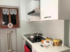 Il comprend une petite cuisine équipée d'une cuisinière et de placards blancs. dans l'établissement Home Christiania by Holiday World, à Sauze dʼOulx