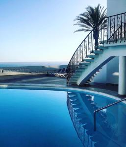 a swimming pool with a staircase and a palm tree at Boutique-Apartment in San Agustin in San Agustin