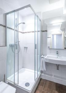 ein weißes Bad mit einer Dusche und einem Waschbecken in der Unterkunft Hotel Zur Krone in Meerbusch