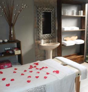 Gala Gala Eco Resort في بونتا دو أورو: حمام مع سرير مع ورود حمراء عليه