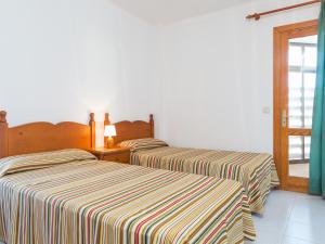 two beds in a white room with striped sheets at Voramar 2h in Port de Pollensa