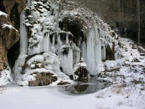 a waterfall covered in snow in a forest at El Refugio in La Cueva