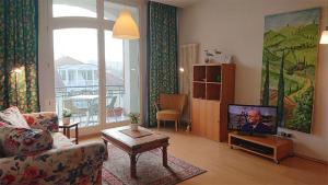 a living room with a couch and a tv at Appartementhaus Waldhaus in Kühlungsborn