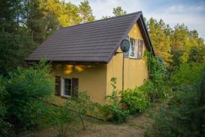 a small yellow house with a black roof at Gospodarstwo agroturystyczne nad jeziorem wśród lasów in Lipnica