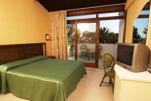 1 dormitorio con 1 cama, TV y balcón en Porto Kaleo Resort, en Steccato