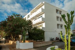 um edifício branco com árvores em frente em Apartamentos Maria - Formentera Vacaciones em Es Pujols