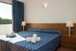 a hotel room with a blue bed with two pillows at Apartamentos Maria - Formentera Vacaciones in Es Pujols