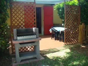 un giardino con griglia e tavolo con porta rossa di Casa Vacanze Guardamare a San Vincenzo