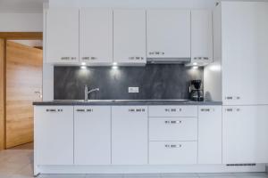 a kitchen with white cabinets and a sink at Hofschenke Pfeiftal - Bergblick in San Martino