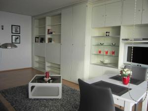a white living room with a table and a tv at Seeblick Apartment in Plaza Maritim Residenz in Timmendorfer Strand