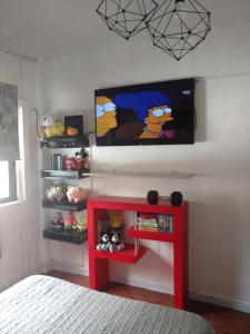 Habitación con TV en la pared y estante rojo. en Hermoso departamento para viajeros en San Fernando