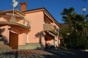 a pink house with a balcony and a palm tree at Apartment Valentina in Opatija
