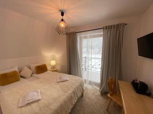 a bedroom with a bed and a large window at Rezydencja Kojsowka in Witów