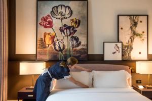 a woman laying on a bed with a painting on the wall at Hotel Vilòn - Small Luxury Hotels of the World in Rome