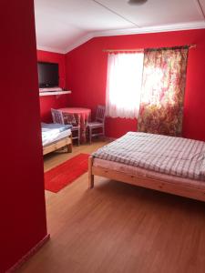 a bedroom with red walls and a bed and a table at BaletyuKatany in Białka Tatrzańska