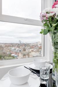 a table with plates and a vase of flowers and a window at WelcomeStay Clapham Junction 2 Bedroom Apartment in London