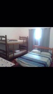 Cette chambre comprend 2 lits, une table et une fenêtre. dans l'établissement Coqueiros Praia Martin de Sá, à Caraguatatuba