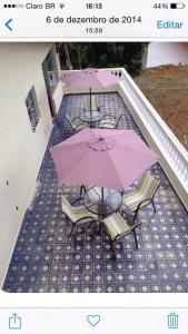 a group of tables and chairs with umbrellas on a roof at Coqueiros Praia Martin de Sá in Caraguatatuba