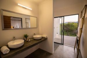 a bathroom with two sinks and a large mirror at Kruger Cliffs Lodge - Absolute privacy guaranteed in Hoedspruit +47 photos