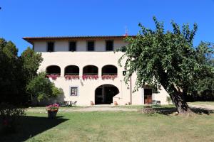 un grand bâtiment blanc avec un arbre en face dans l'établissement Antico Borgo La Torre Agriturismo, à Reggello