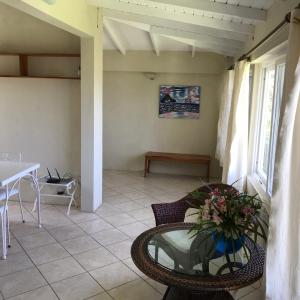 een woonkamer met een tafel, een stoel en een raam bij Romantic Cottage in Sauteurs