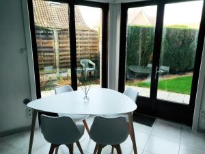 een witte tafel en stoelen in een kamer met een raam bij Maison familiale tout confort avec garage in Lompret