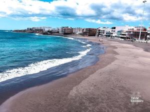 une plage avec l'océan et des bâtiments en arrière-plan dans l'établissement SALINETAS BLUE SURF HOUSE, à Telde