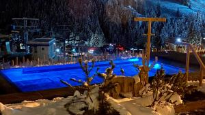 una piscina cubierta de nieve por la noche en Dolasilla Mountain Panoramic Wellness Hotel, en La Villa