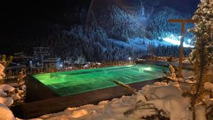 una piscina coperta di neve di notte di Dolasilla Mountain Panoramic Wellness Hotel a La Villa