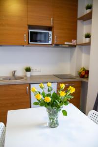 wazon z żółtych kwiatów na stole w kuchni w obiekcie Sky Studio near the Vilnius Center w Wilnie