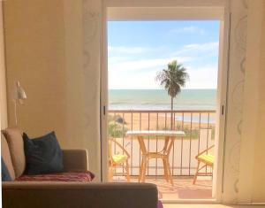 a living room with a view of the ocean from a balcony at Frente al mar 1ª línea de playa in Conil de la Frontera