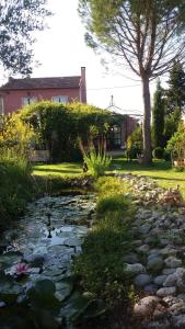 einen Garten mit einem Teich vor einem Haus in der Unterkunft La Maison de Maïté in Cheval-Blanc