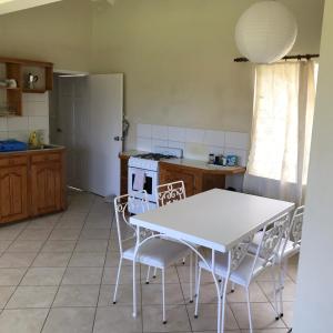 a kitchen with a white table and chairs at Romantic Cottage in Sauteurs