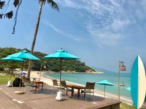 a table and chairs with umbrellas on a beach at The Bay Samui in Choeng Mon Beach