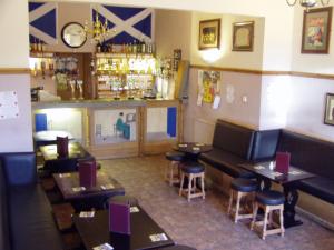 a restaurant with tables and stools and a bar at Auld Mill House Hotel in Dunfermline