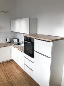 a kitchen with white cabinets and a wooden floor at Ferienapartment Warnemünde 2 in Warnemünde