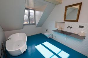 bagno con servizi igienici bianchi e pavimento blu di Fleur de Lis a Le Locle