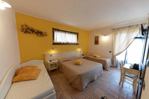 a bedroom with two beds and a desk and a window at Agriturismo La Dimora Del Contadino in Mondovì