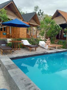 a woman sitting on a chair next to a swimming pool at Agasta Villa in Nusa Penida