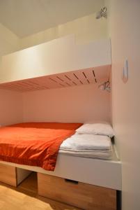 a white bunk bed with an orange blanket on it at Ylläshuiput in Ylläsjärvi