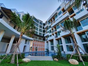 a building with palm trees in front of it at Atom Phuket Hotel -SHA Plus in Nai Yang Beach